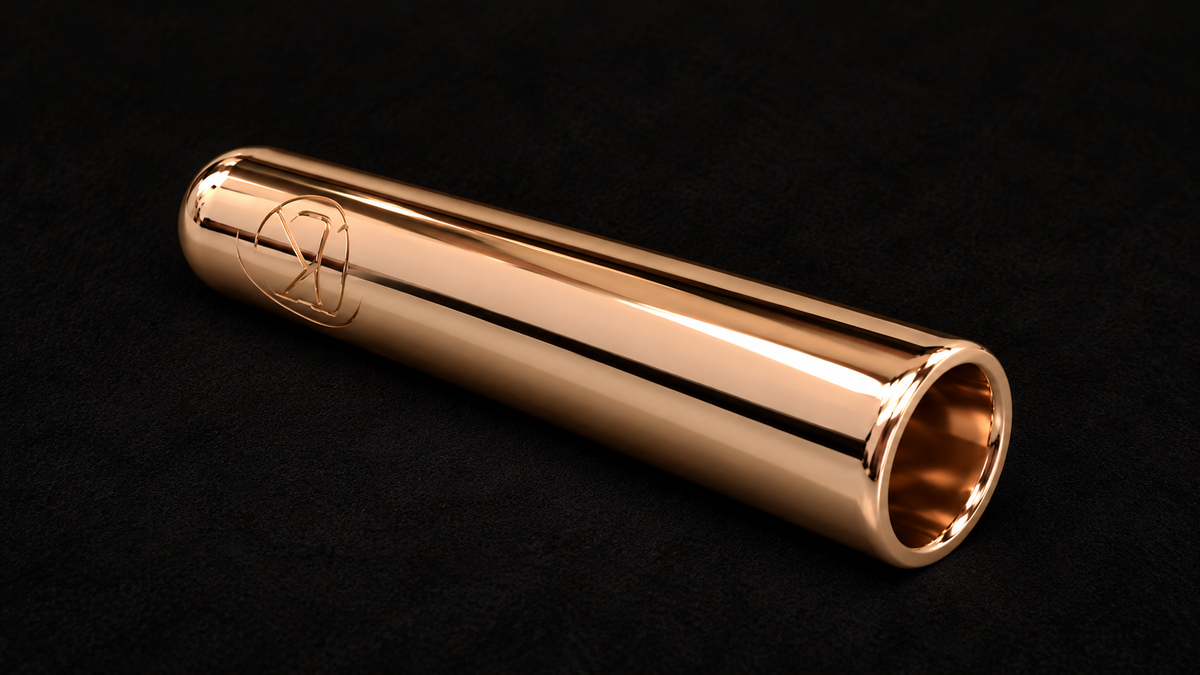 KORTONS polished rose gold lace aglet with engraved logo, photographed on a smooth all-black suede background.