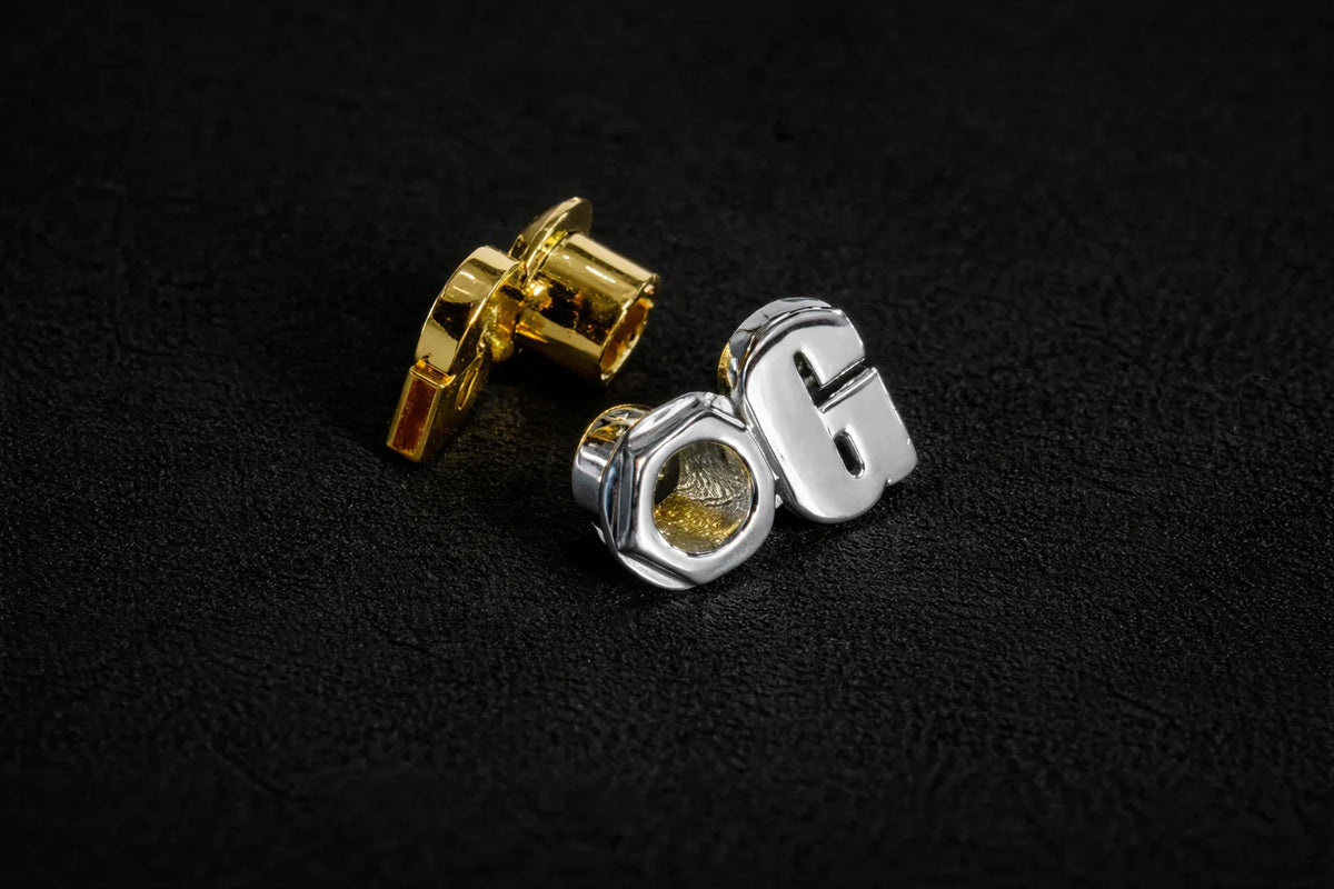 KORTONS polished metal eyelets and aglets components shown in gold and platinum on a dark surface