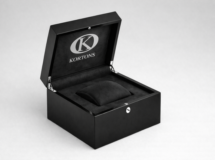 Open KORTONS black luxury eyelet box with glossy exterior and black suede interior, featuring a centered cushion insert and engraved K logo, presented in a clean, minimal studio setting.
