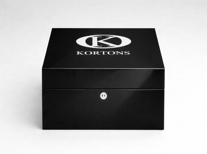 Closed glossy black KORTONS eyelet box with centered logo and front lock detail, presented in a clean studio setting to emphasize luxury footwear hardware packaging.