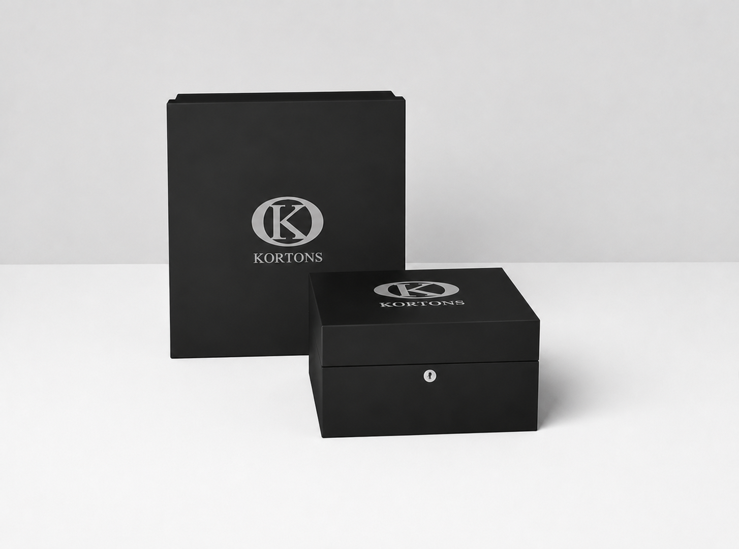 KORTONS luxury presentation box displayed before a matching signature packaging box on a clean light backdrop, featuring black semi-gloss finishes, refined proportions, and minimalist brand presentation.